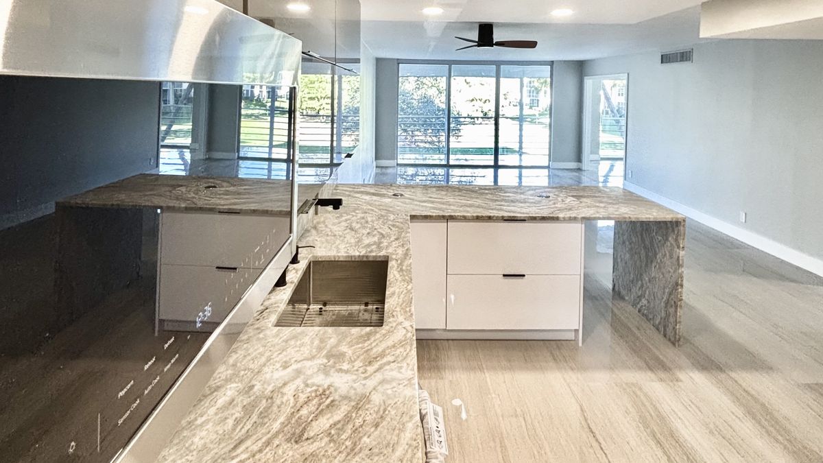 Open kitchen with stone waterfall island and floor-to-ceiling windows overlooking the golf course, 545 Oaks Lane #201, Pompano Beach